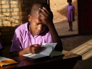 A student studies in the early morning sunlight at Emmanuel Christian School in Nsaalu, Uganda, where they lack electricity and running water. 